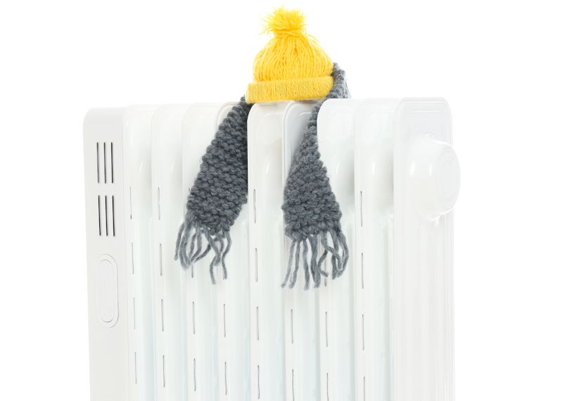 Radiador con un gorro y bufanda encima. Climatización portátil.